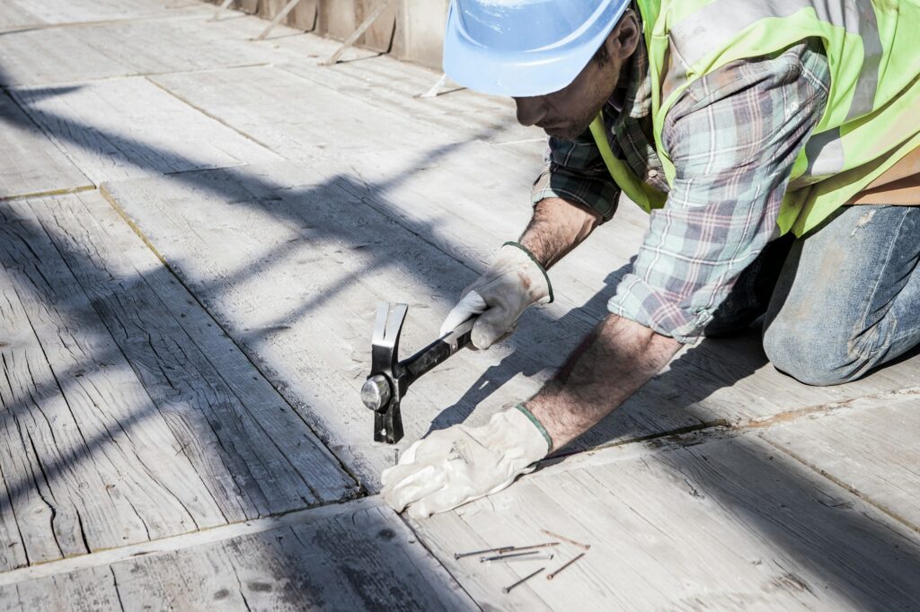 A carpenter hammers nails into wooden planks with a hammer.