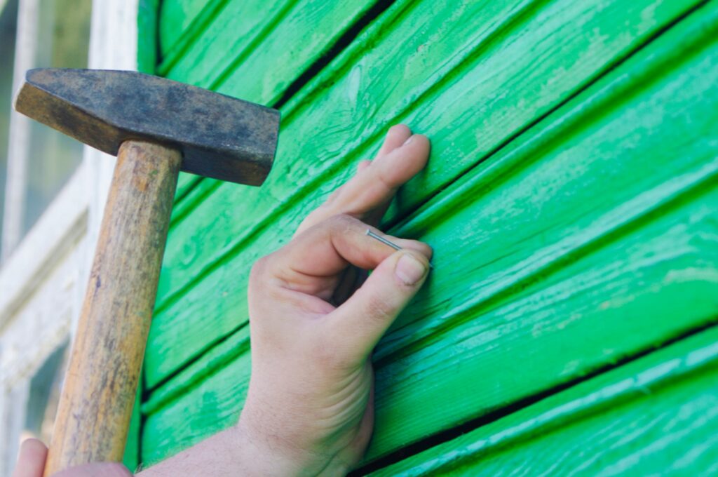 a man hammers a nail into a wooden wall with a hammer