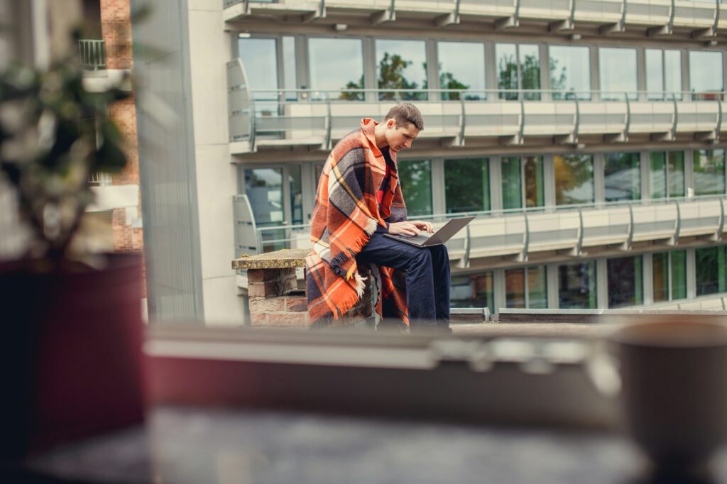 A man using laptop on the roof.