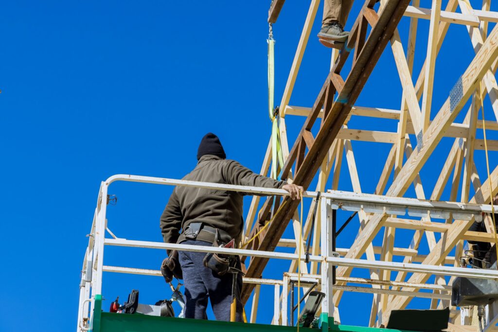 Man hammers nails into wooden frame on roof carpentry work on roof of wooden house